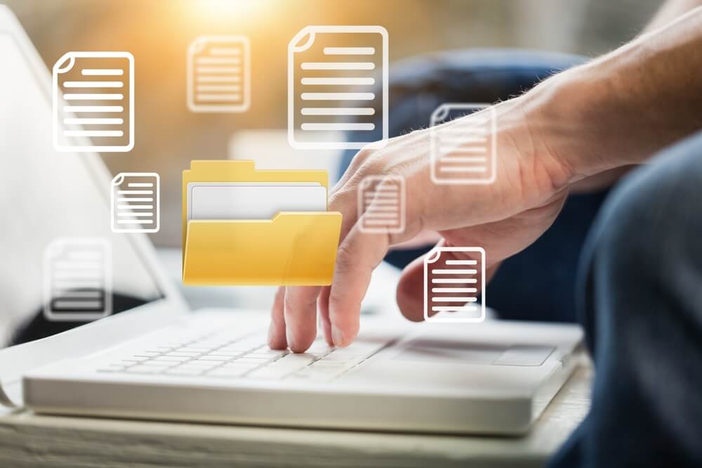Person typing on a laptop with floating document icons, symbolizing tax information collection for preparation during tax season.