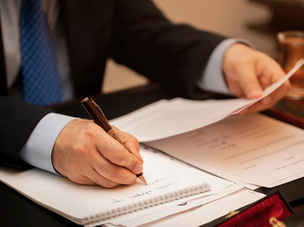 Person in a suit writing notes on paperwork, symbolizing tax resolution and legal representation services at Mid-Atlantic Law and Tax.